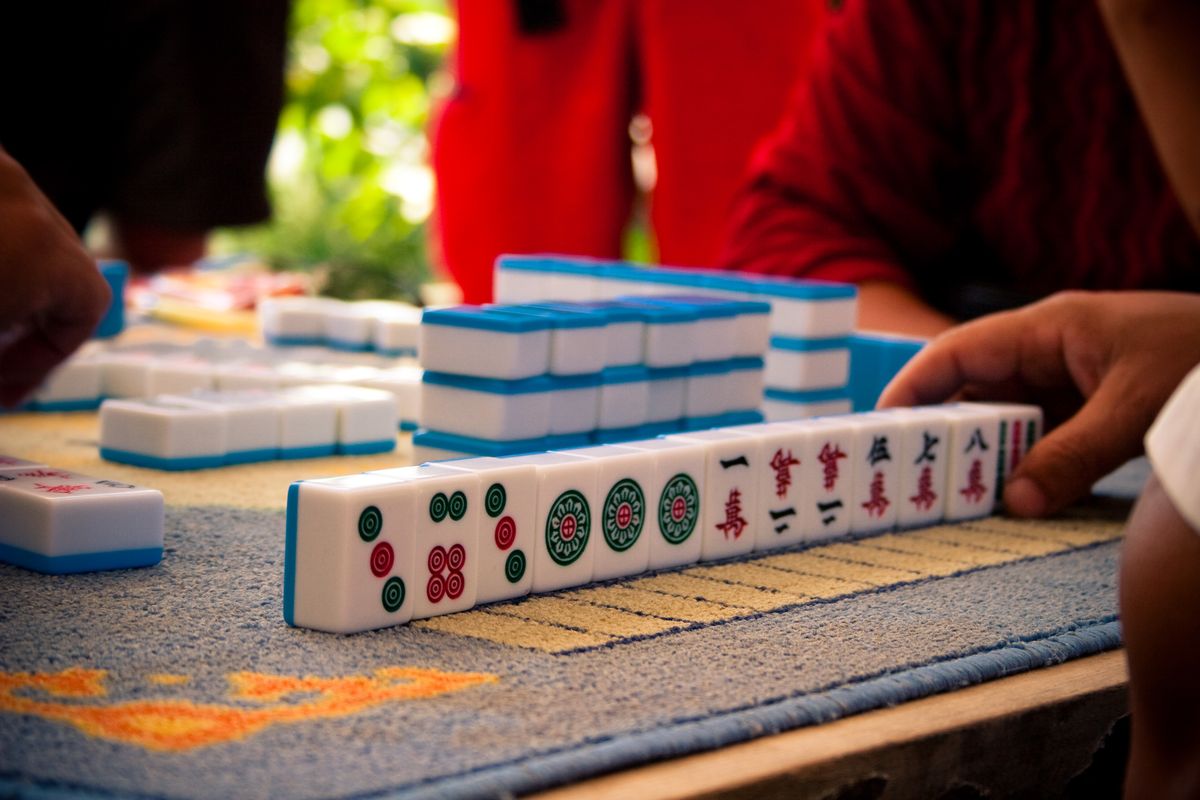 A player arranging a rack of tiles while planning a mahjong strategy