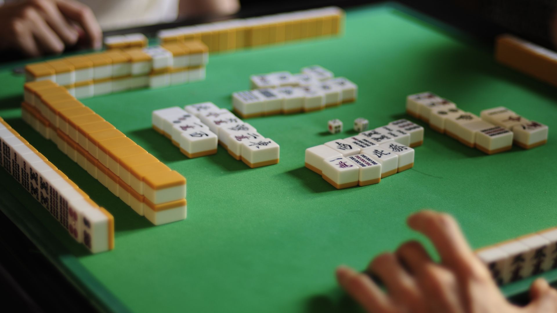 Mahjong Malaysia style game in progress on green baize, with the tile walls and discards on the table